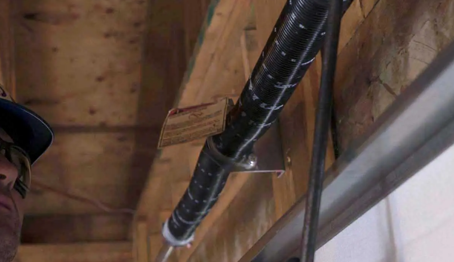 a technician performing a garage door spring repair, showcasing the detailed work involved in fixing a broken spring, at Clintonville Garage Door Repair.