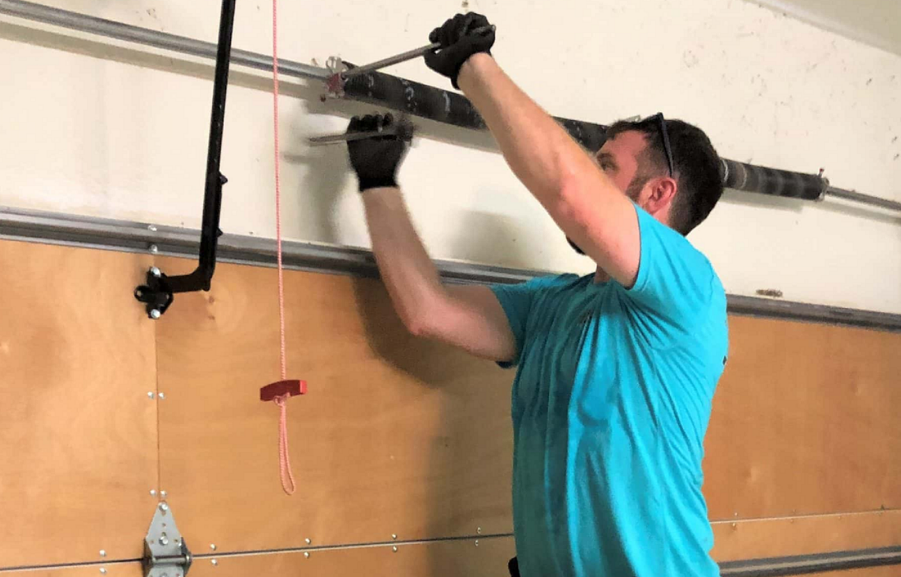 A technician from Clintonville Garage Door Repair performing a garage door spring repair on a residential garage, showcasing expertise and precision in garage maintenance.